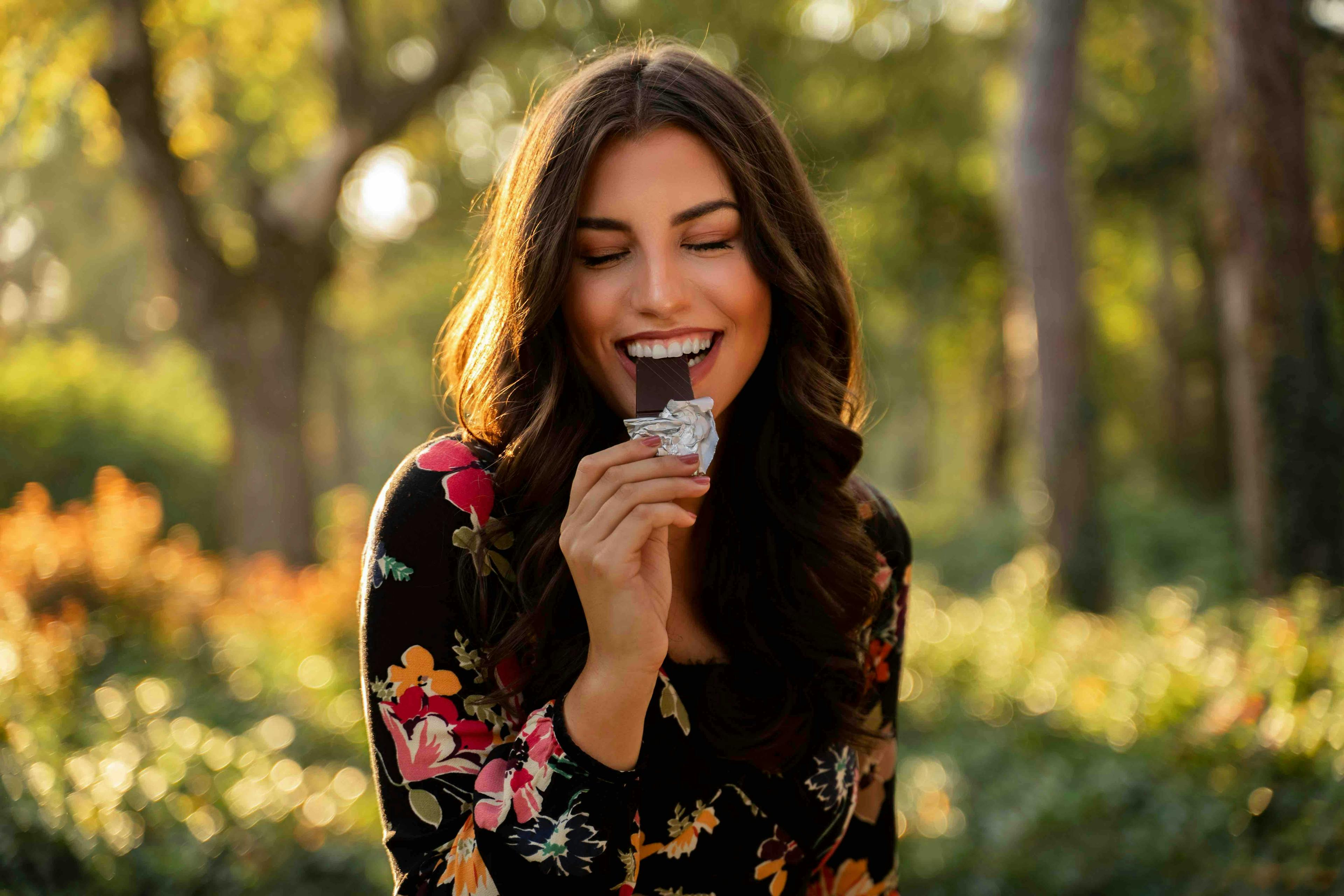woman,beauty,gorgeous woman,young,caucasian,happy,cute,enjoying,smile,beautiful,bite,brunette,female,sunny,park,eyes closed,pretty,nature,one,girl,portrait,positive energy,food,lifestyle,chocolate bar,outdoor,eats,healthy,charming head person face happy laughing